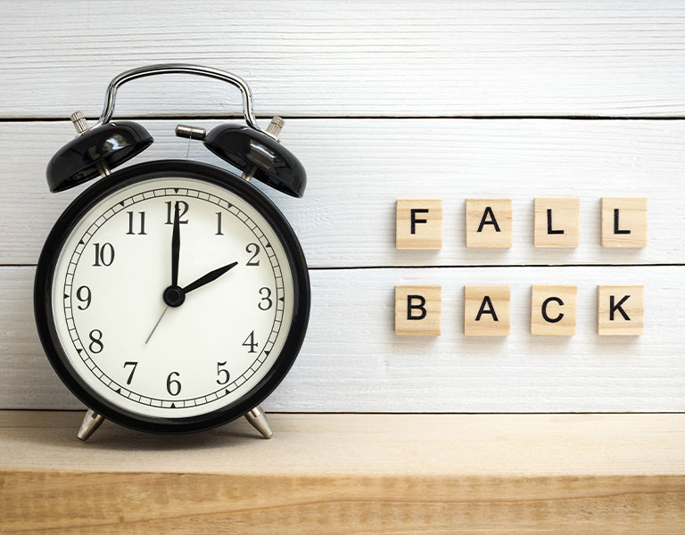 an analog clock and tiles that spell FALL BACK