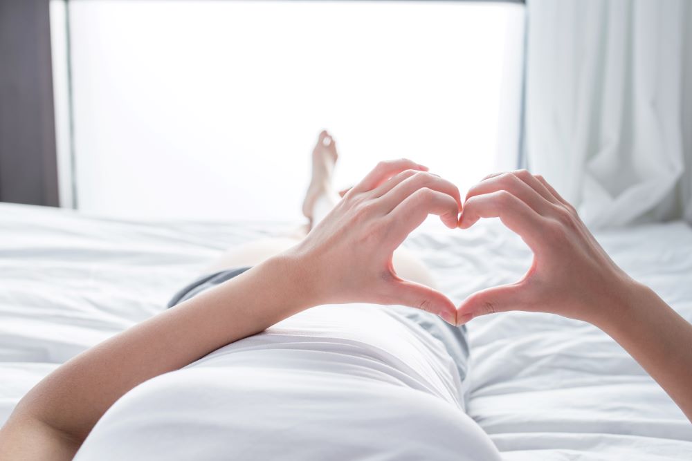 people holding hands in the shape of a heart in bed