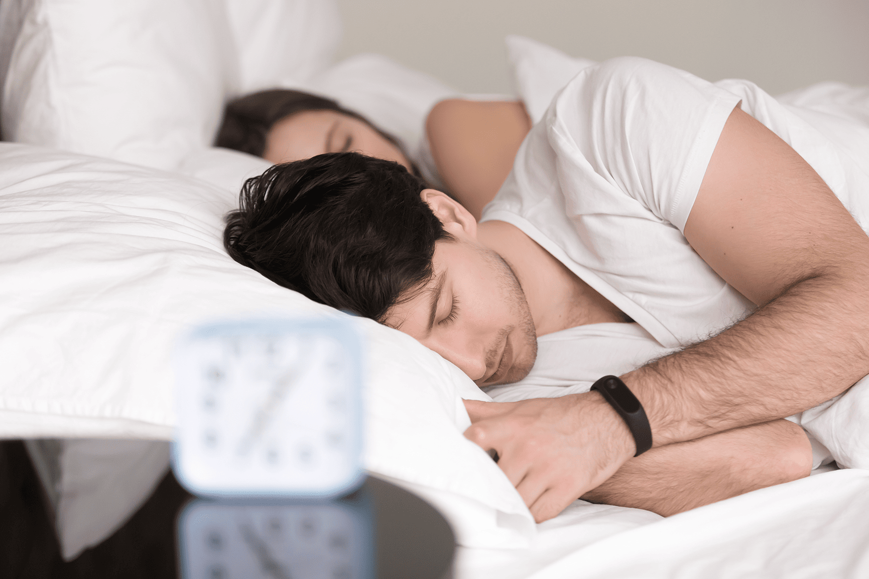 couple-lying-asleep-bed-man-wearing-wristband-smart-watch